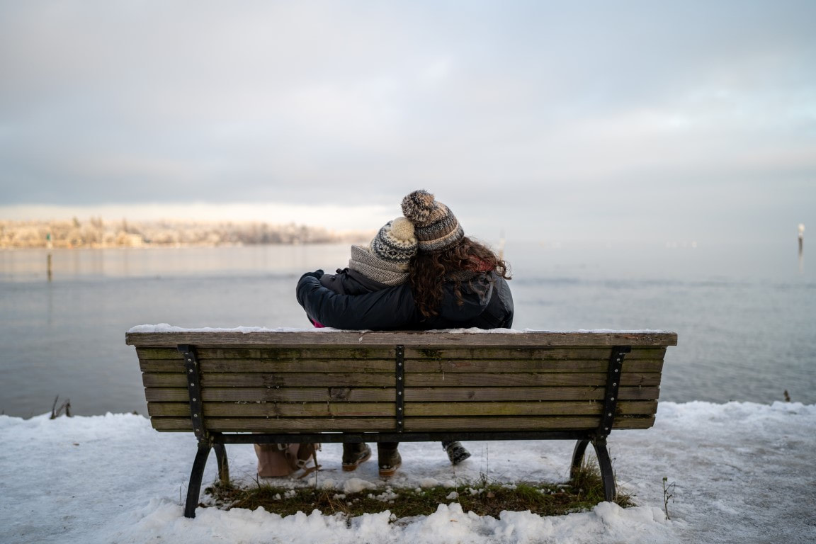 Cute couple sitting on a bench looking out on Lake Konstanz, Bodensee
